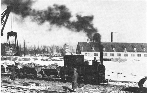 二號火葬場前的火車照片，圖片右方的小幢建築物為二號火葬場，可隱約看見注入毒氣的煙囪。